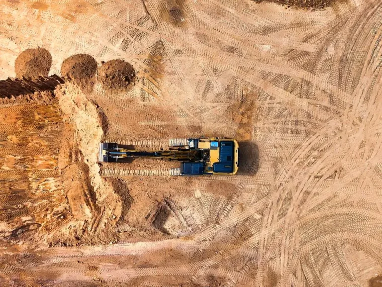 Aerial view of an excavator grading a cleared construction lot