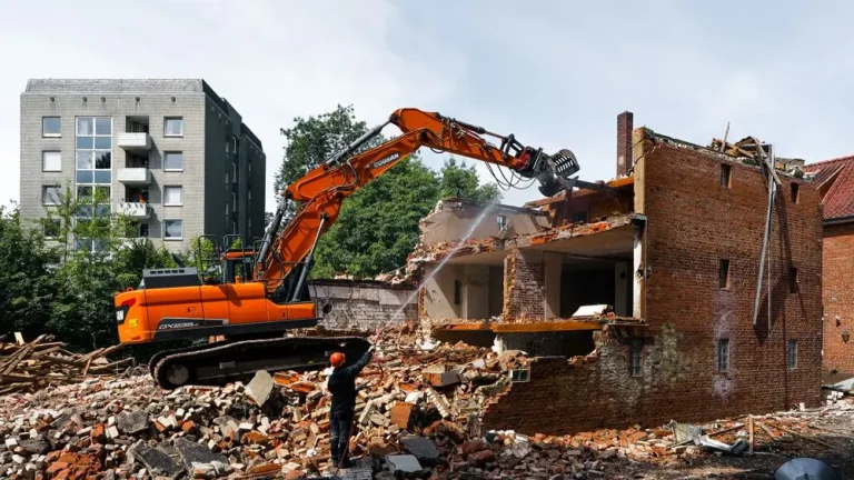 Excavator tearing down an old building during a full structure demolition