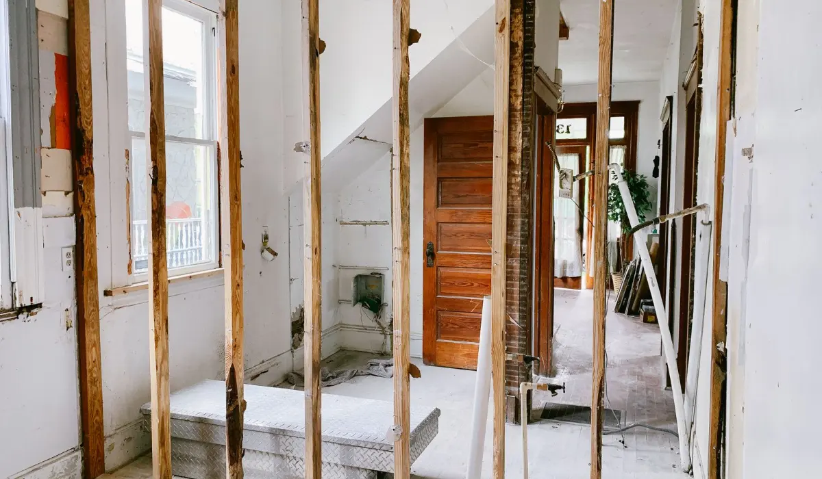Home interior under renovation with exposed wood wall framing and a doorway, checking whether a wall is load bearing