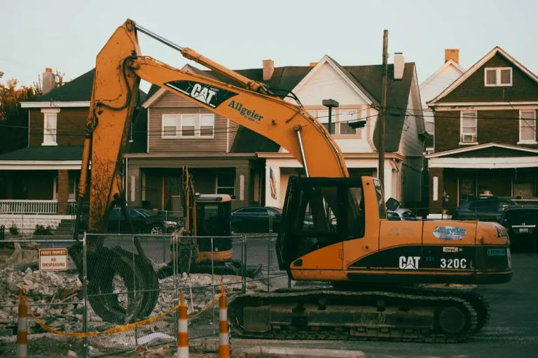 Excavator working on a residential demolition and site prep job between neighborhood homes