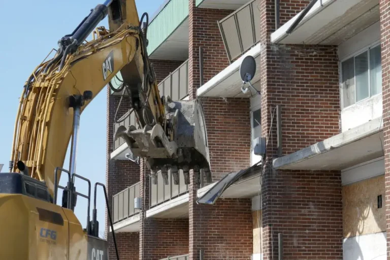 Excavator demolishing a brick residential building